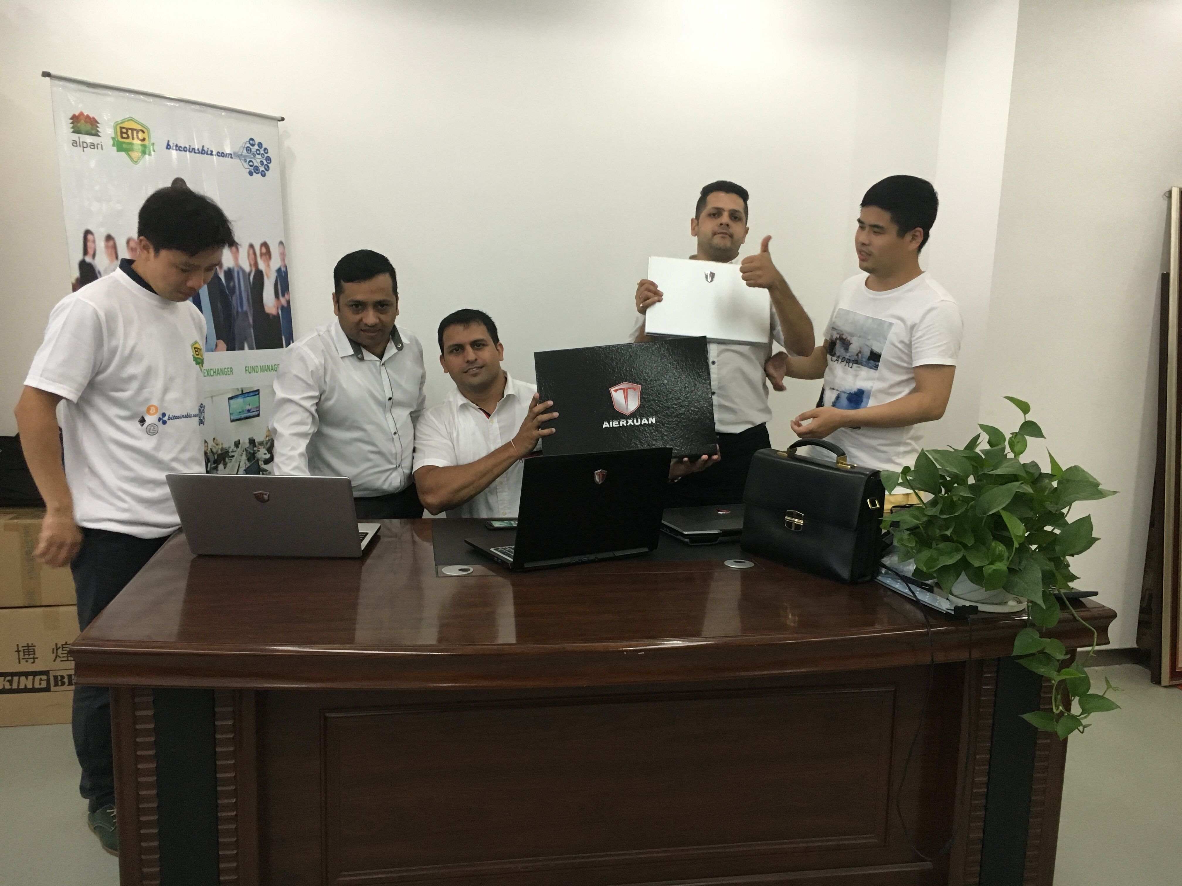 Team showcasing AIERXUAN laptops with partners